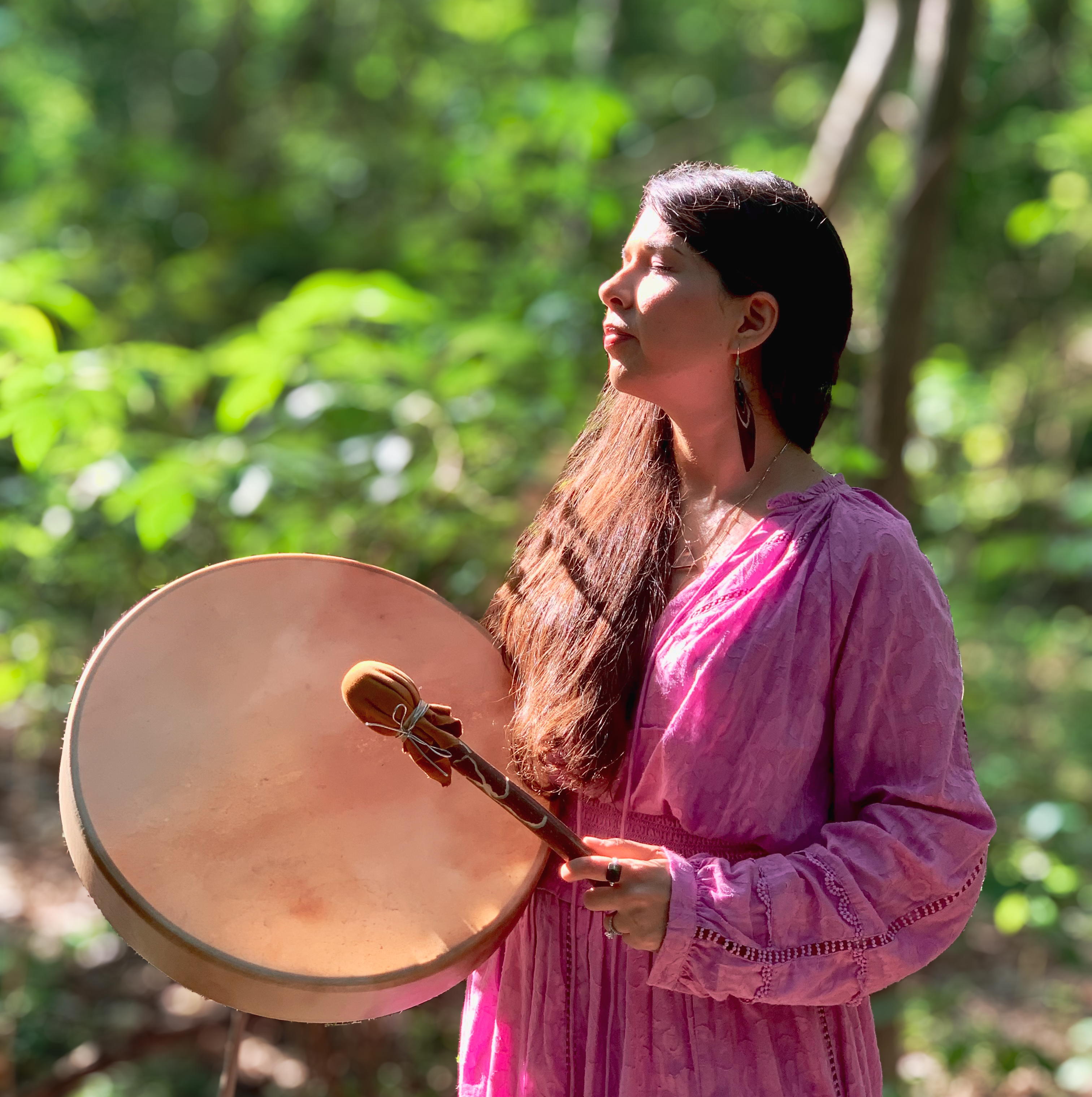 Laura Maesaka, spiritual coach and energy healer, playing a drum outdoors